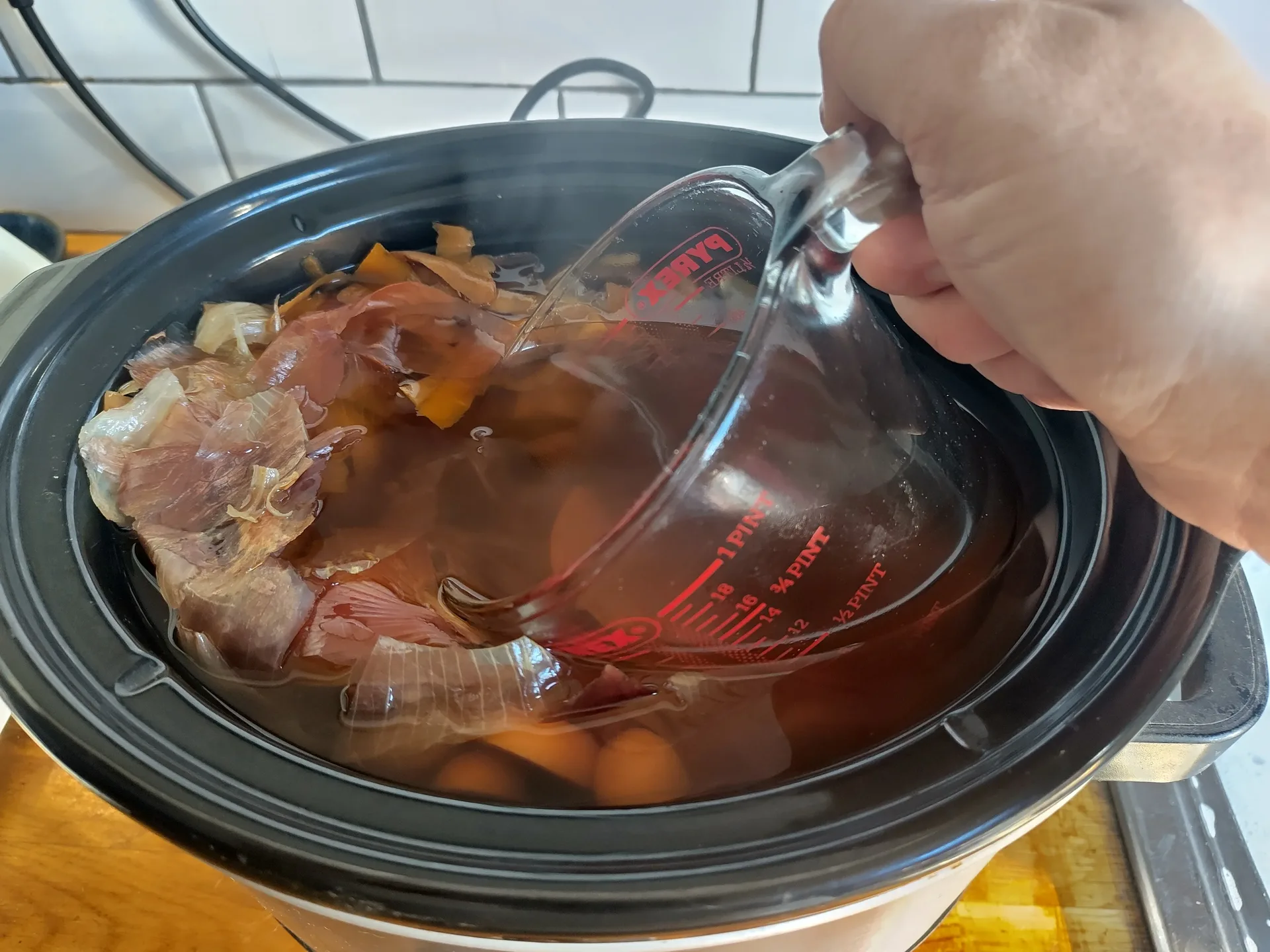 Scooping stock out of the slow cooker with a measuring jug