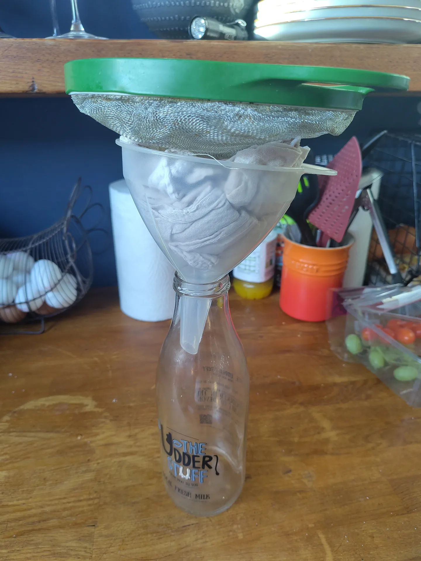 A funnel placed in a bottle, with a muslin cloth and sieve on top